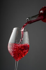 Pouring pink wine from a bottle into a glass.