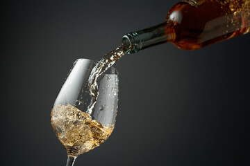 Pouring white wine from a bottle into a glass.