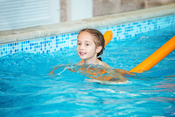 Child girl learns to swim in the swimming pool. Children sport, training, fitness for kids.