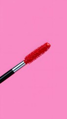 Red mascara brush on pink background, close-up view