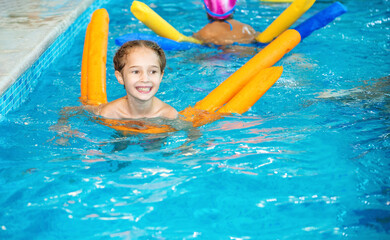 Swimming aids help children learn to swim. Fun group training for children in the pool. Sports funny background