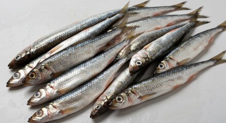 A pile of small, silver, raw fish with details, lying on a surface