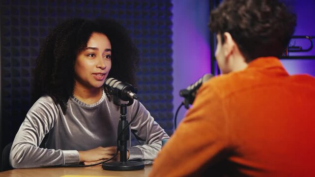 Smiling Black female podcast host giving high-five to male guest after interview