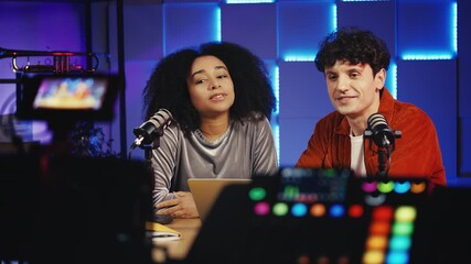 Female radio host and male colleague recording podcast together in studio