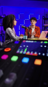 Male radio host interviewing Black female guest while recording podcast
