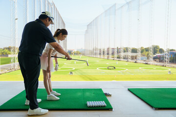 Golf instructor correcting grip technique for beginner woman