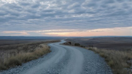 Winding Road Through Vast Landscape at Dusk Under Cloudy Sky.
