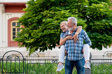 Happy senior couple having fun and enjoying outdoor piggyback ride
