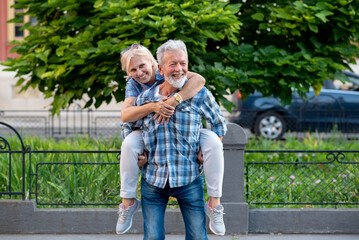 Happy senior couple having fun and enjoying outdoor piggyback ride