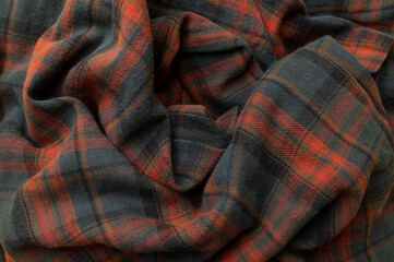 Texture of wrinkled plaid blue green red brown cotton flannel fabric, top view. Tartan pattern, textile for shirt, clothing, tablecloth. Checkered print, Christmas New Year textile pattern
