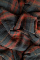 Texture of wrinkled plaid blue green red brown cotton flannel fabric, top view. Tartan pattern, textile for shirt, clothing, tablecloth. Checkered print, Christmas New Year textile pattern