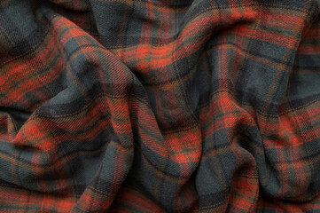 Texture of wrinkled plaid blue green red brown cotton flannel fabric, top view. Tartan pattern, textile for shirt, clothing, tablecloth. Checkered print, Christmas New Year textile pattern