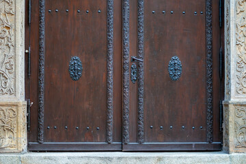 Historic double wooden doors with metal fittings set in stone portal architectural detail close up