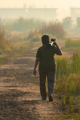 Female Wildlife Photographer Walking Through Foggy Forest with Telephoto Lens