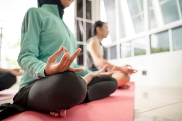 Fototapete Rund Lotusblume Indonesian southeast asian people meditating in a lotus position on a yoga mat indoors. She has her eyes closed and is practicing mindfulness  © Leo Lintang