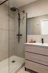 Modern bathroom with a glass shower enclosure, wooden vanity, and minimalist decor. Neutral color palette creates a serene atmosphere.
