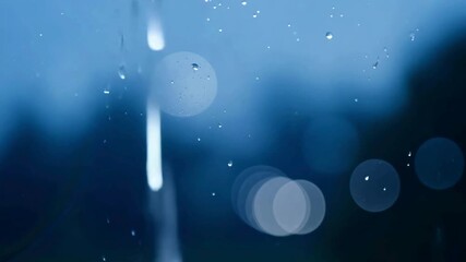 Close up of raindrops trickling down a window pane with a soft blue blurry background and light bokeh effects. - Powered by Adobe