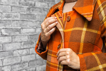 a woman unbuttons the top button of her coat, close-up. A woman unbuttons her coat. women's fingers fastening a button. woman trying on coat. autumn coat. top button. checked coat. 
