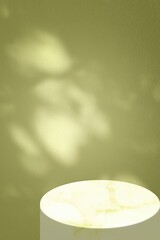 Minimalist Product Display with Leaf Shadows on Yellow Green Wall and Marble Stand.