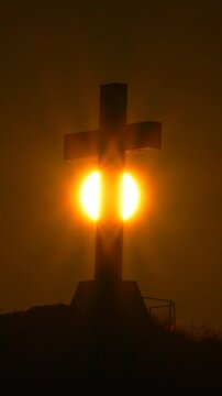 Cross Sunset Silhouette, golden sun behind large religious cross, spiritual and serene, vertical video