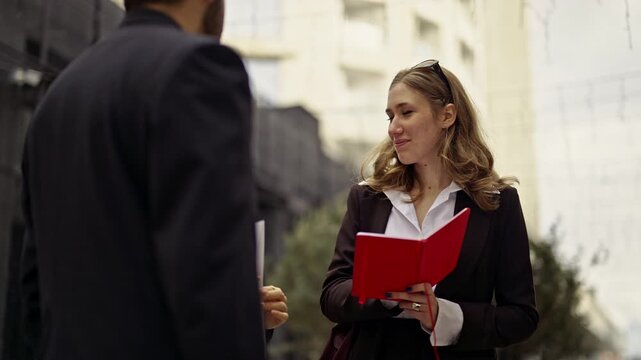 Three business people, two women and a man, are having an outdoor meeting, discussing a project. They are collaborating remotely, highlighting the flexibility of modern work environments.