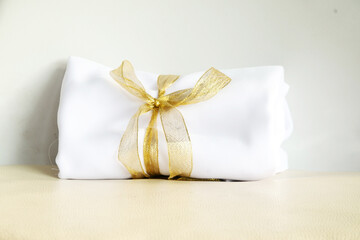 Folded White Fabric with Golden Ribbon Bow