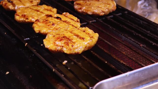 Close-up view of meat cutlets fried on the grill. The process of cooking street food. Real time motion video.