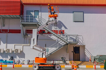 Workers are working on the Orange articulate boom lift or telescopic boom lifts and bucket crane mounted on truck for working at heights and articulating boom lift