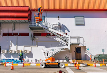 Workers are working on the Orange articulate boom lift or telescopic boom lifts and bucket crane mounted on truck for working at heights and articulating boom lift