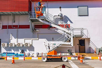 Workers are working on the Orange articulate boom lift or telescopic boom lifts and bucket crane mounted on truck for working at heights and articulating boom lift
