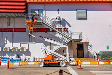 Workers are working on the Orange articulate boom lift or telescopic boom lifts and bucket crane mounted on truck for working at heights and articulating boom lift