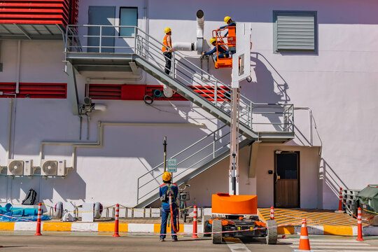 Workers are working on the Orange articulate boom lift or telescopic boom lifts and bucket crane mounted on truck for working at heights and articulating boom lift