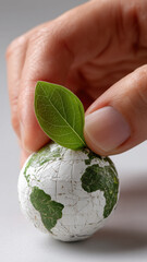 Conceptual image of a hand placing a leaf on a globe, representing environmental conservation and the importance of sustainable practices.