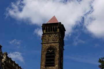 Historic Architecture: Antique Clock Tower With Red Roof And Stonework Under Blue Sky With Dramatic Clouds