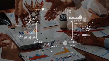 A dynamic office scene featuring multiple hands engaged in a collaborative meeting, surrounded by charts and digital graphics, emphasizing teamwork and strategy development. Raster