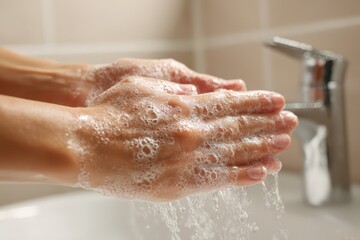 Fototapeta premium Hygiene moment: lathering soap on hands at a sink with foamy bubbles