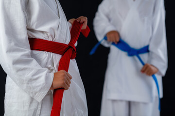 Two boys demonstrating karate hand positions and belt alignment on dark backdrop. Emphasizes structure, balance, and controlled martial arts form.