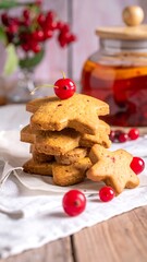 Stacked, golden-brown star-shaped cookies are adorned with a single red cherry and small red berries on a linen napkin