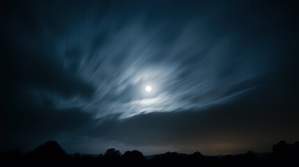 Obraz premium Moonlit night sky with a full moon behind dark drifting clouds