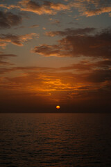 A spectacular sunset over the Atlantic Ocean, with the orange sun dipping into the horizon. The photo was taken from the coast of Mog&aacute;n, Gran Canaria, Spain