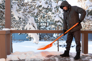 Worker man removes snow near house outdoor
