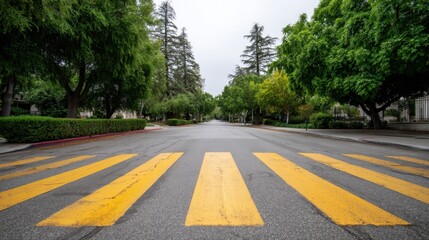 Obraz premium Serene Urban Street with Yellow Crosswalk Under Overcast Sky Surrounded by Lush Green Trees and Calm Atmosphere in City Neighborhood