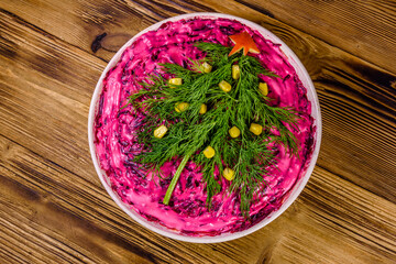 Ceramic plate with russian traditional new year salad herring under fur coat (shuba) decorated with christmas tree made from dill on rustic wooden table. Top view