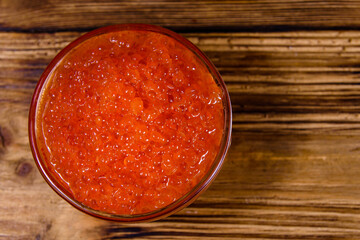 Glass bowl with red caviar on a wooden table. Top view