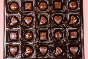 Heap of chocolate candies in a brown box. Top view