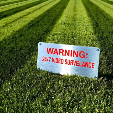 Warning sign placed within an open grassy field, indicating restricted or controlled territory in a rural or undeveloped landscape environment