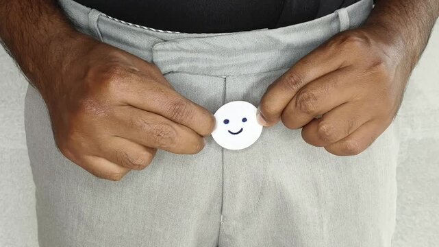 Asian or indian man shows a happy paper face near pant zipper. Sperm donation awareness. Impotence, oligospermia, prostate cancer, phimosis, powerlessness and infertility disease treatment concept.
