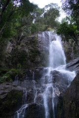 Fototapeta premium A waterfall is flowing down a rocky cliff. Walking Trail Hiking forest concept.