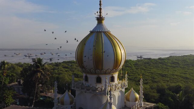 Wide circular drone orbit around coastal domed mausoleum architecture