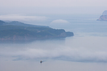 Aerial view of the bay. The tugboat is sailing along the bay. Fog over the water. Beautiful morning seascape. Avacha Bay, Pacific Ocean. Kamchatka Peninsula, Far East of Russia.